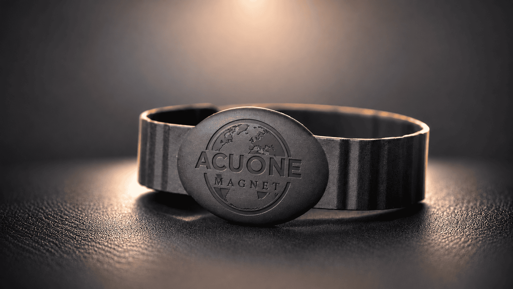 AcuOne 1 Bracelet AcuOne Magnet noir et logo gravé, éclairés d’une lumière chaude sur fond sombre.